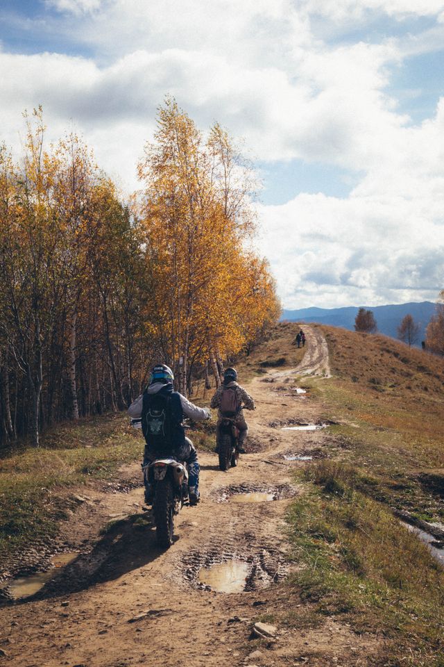 Two riders in full kit riding an autumn trail