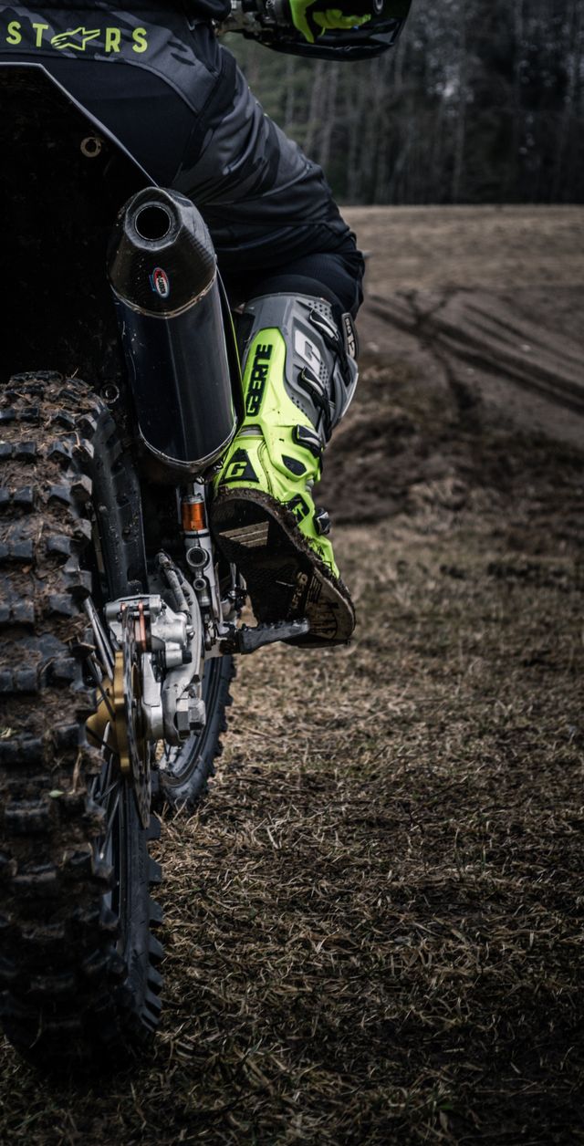 Close-up of a rider's boot and the exhaust of a trail motorcycle