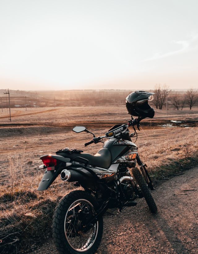 A motorcycle parked on a dirt track at golden hour