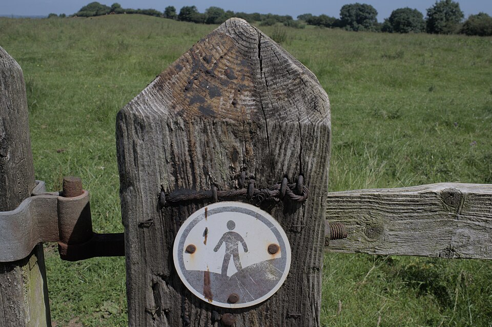 An Open Access Land waymark disc showing a walking figure, fixed to a wooden gatepost