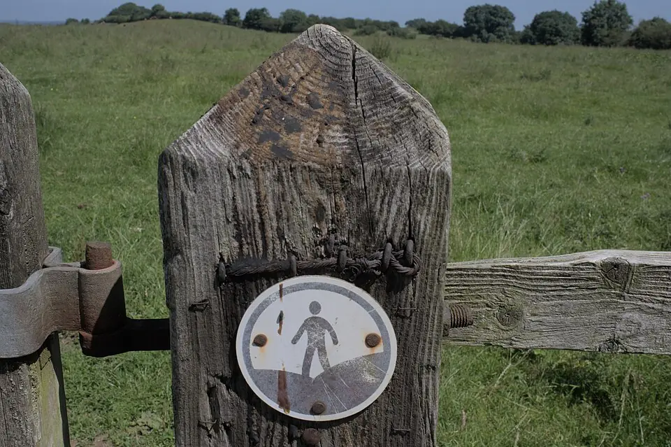 An Open Access Land waymark disc showing a walking figure, fixed to a wooden gatepost