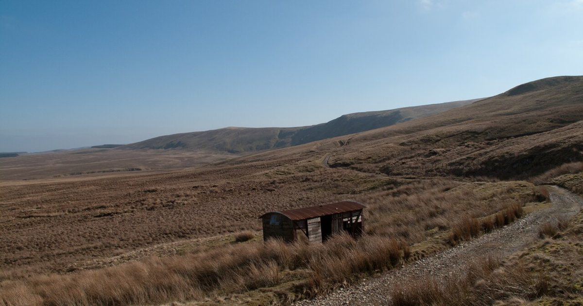 The Old Coach Road below Clough Head in the Lake District, a track crossing brown moorland past a small hut