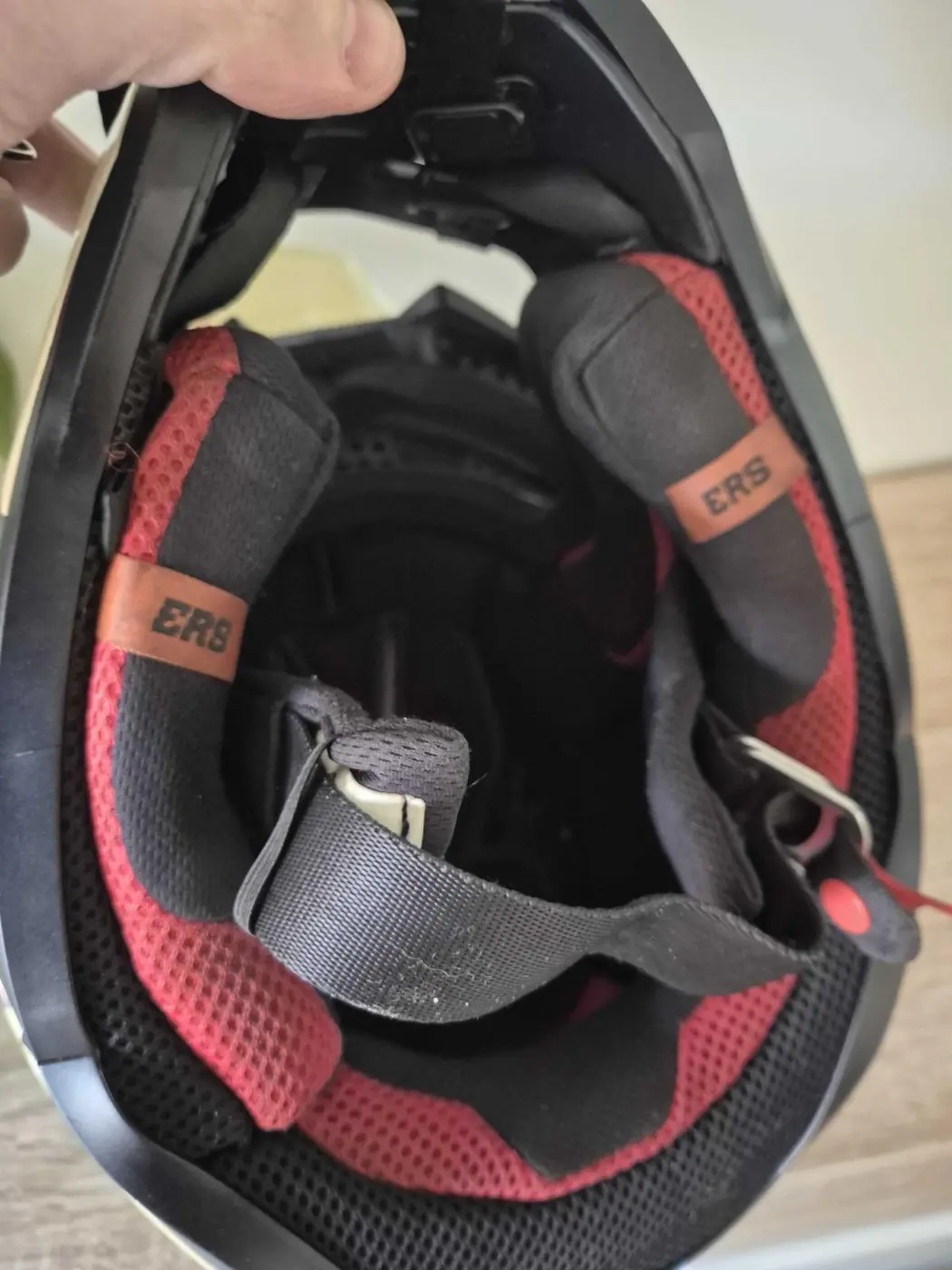 Inside the Alpinestars SM5 showing the red and black liner, emergency release cheek pad tabs and double-D chin strap