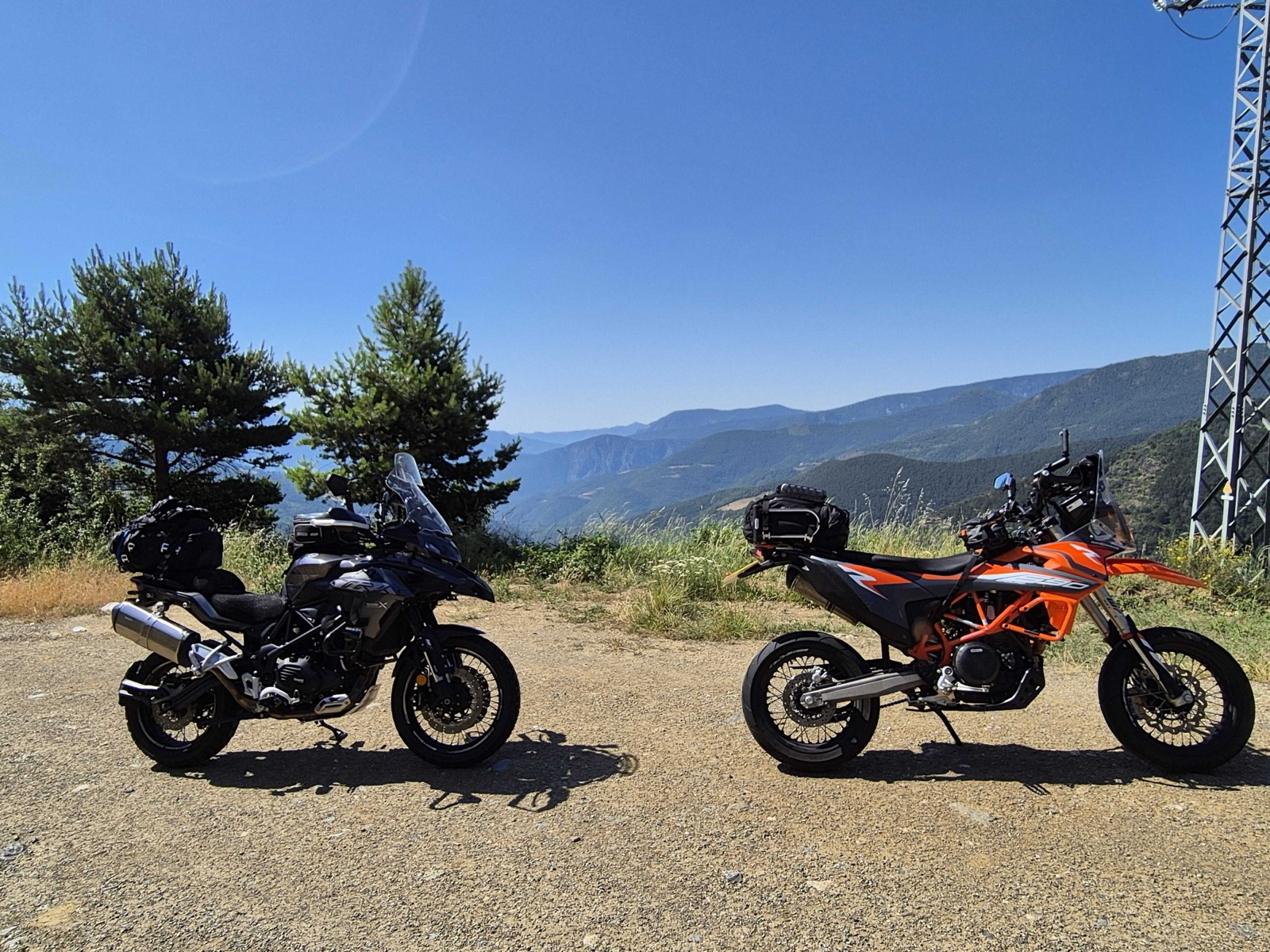 Benelli TRK 502 X parked next to a KTM 690 SMC R at a mountain viewpoint in the Pyrenees, showing the size difference