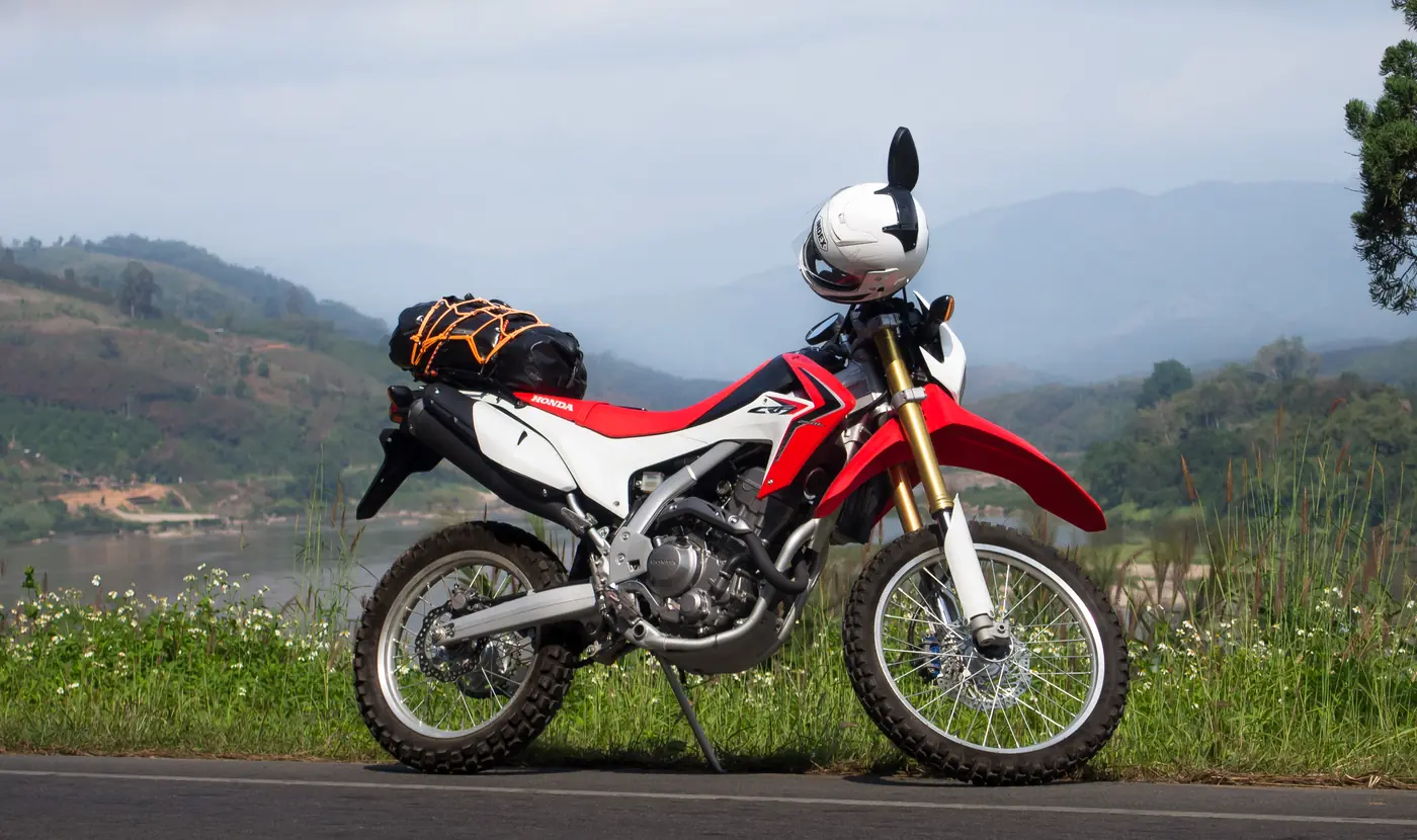 A small trail motorcycle parked on a green lane
