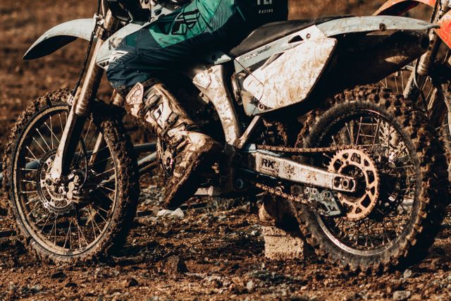 A muddy rear wheel, chain and sprocket on a dirt bike