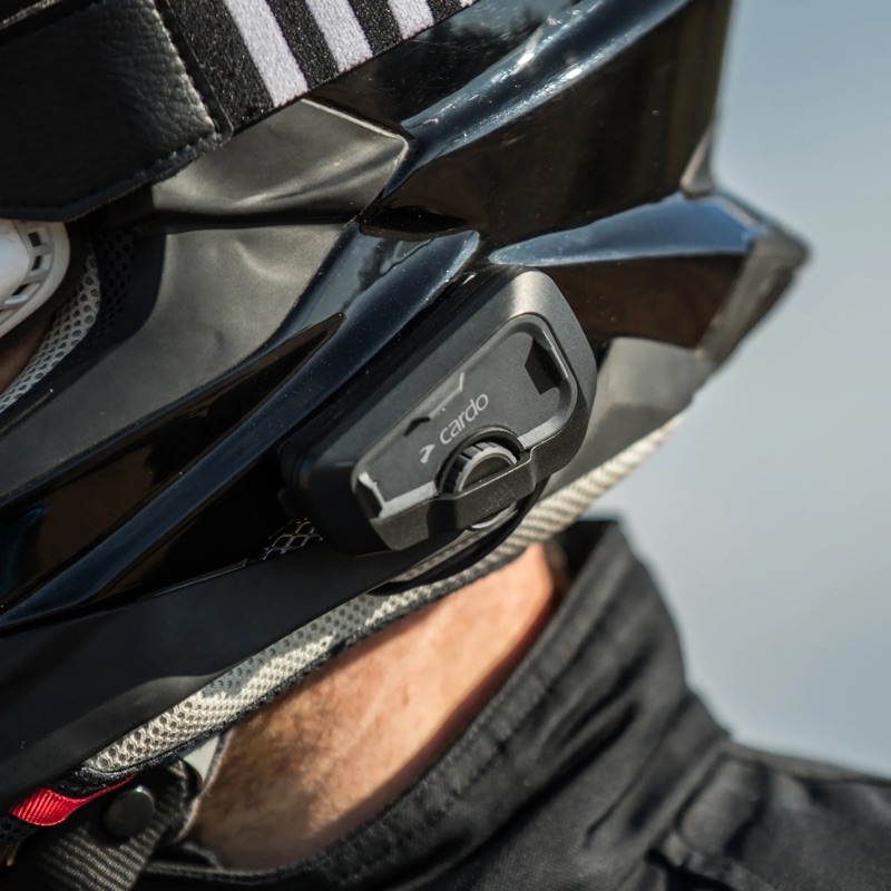 A Cardo Freecom 4X fitted to the side of an adventure helmet