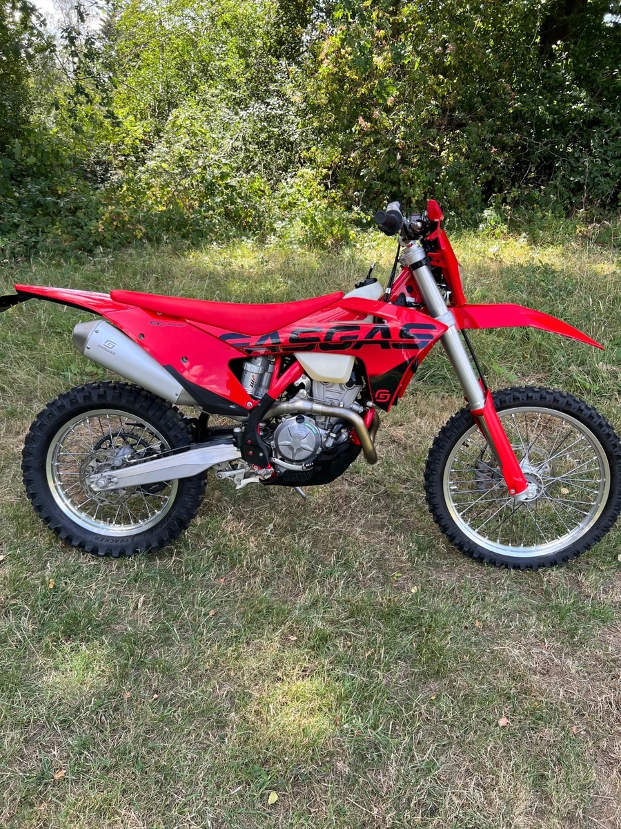 A red GasGas enduro parked in long grass, the same kind of bike Mark rides for the more technical days