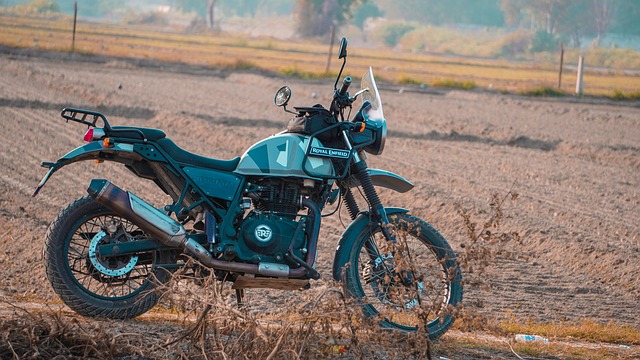 a Royal Enfield Himalayan parked at the edge of a ploughed field