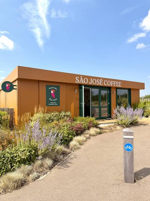 São José Coffee, a small orange building with green doors and a planted garden, at Graze Hill in Bedford